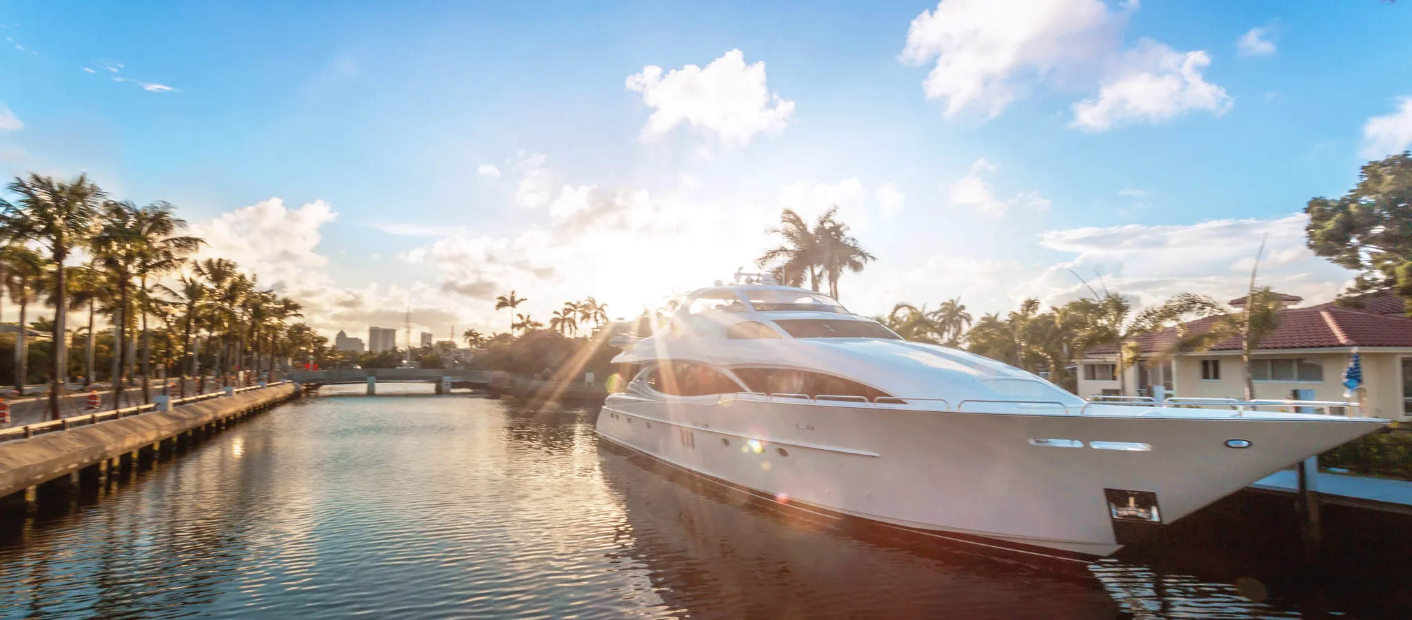 Estate, wealth, yachts, marina, retirement. Front view of the sun coming down at Fort Lauderdale canals. Yachts moored on canal against cloudy sky at sunset in Las Olas Boulevard, Fort Lauderdale. Perhaps an estate and wealth planning themed stock photo.