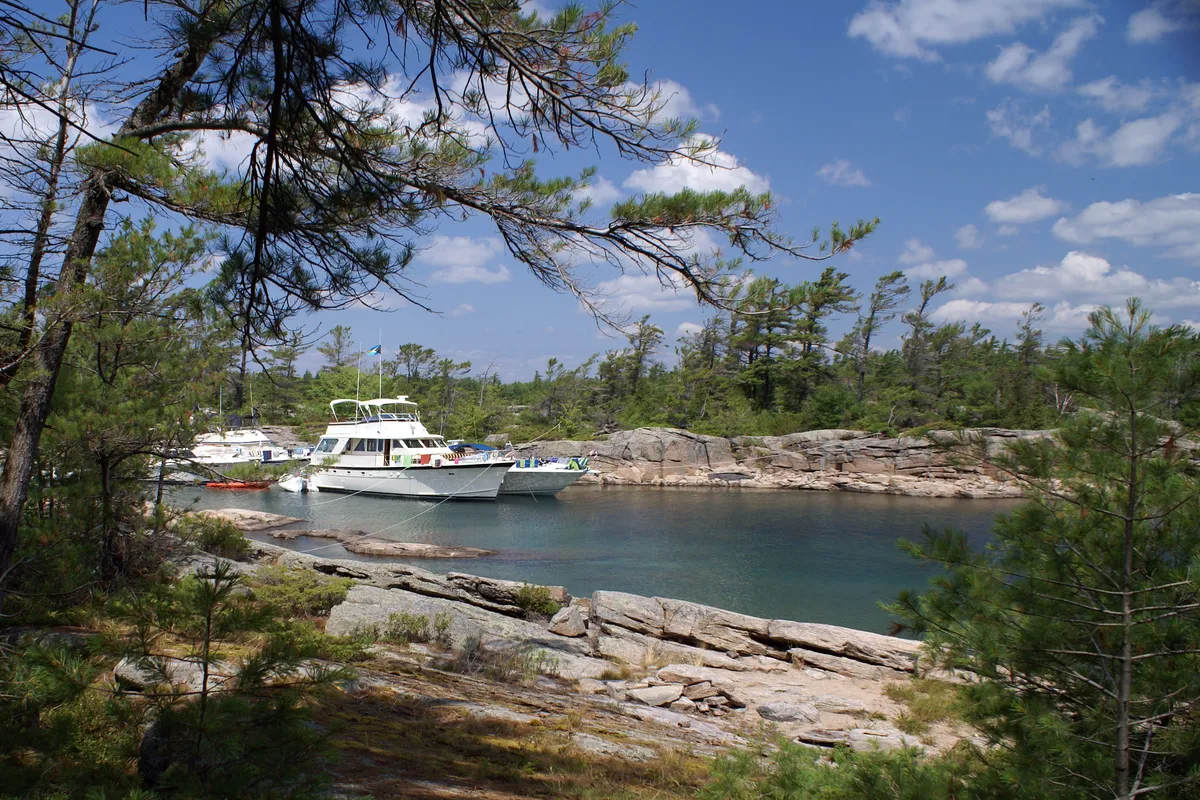 Large yachts between rocky islands in Killarney or near Georgian Bay. A stock photo on themes of vacation, luxury, retirement, wealth, nature.