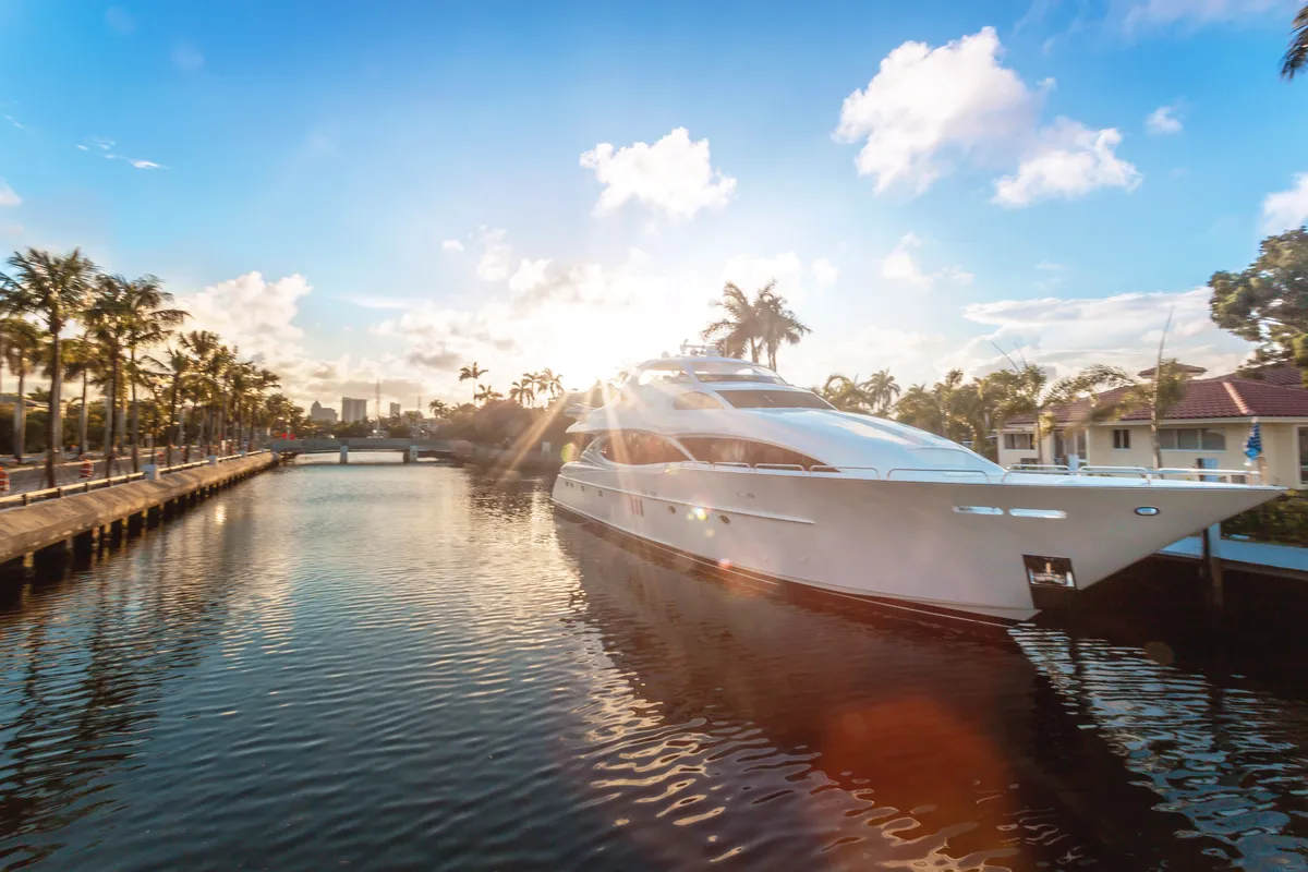 Yachts moored on canal against cloudy sky at sunset in Las Olas Boulevard, Fort Lauderdale. A wealth themed stock photo.
